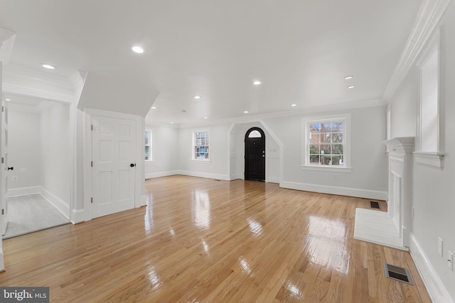 unfurnished living room featuring crown molding, plenty of natural light, and light hardwood / wood-style floors