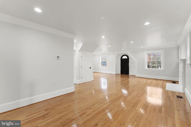 unfurnished living room with ornamental molding and light wood-type flooring