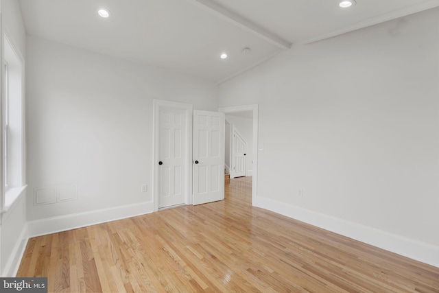 empty room with lofted ceiling with beams and light wood-type flooring