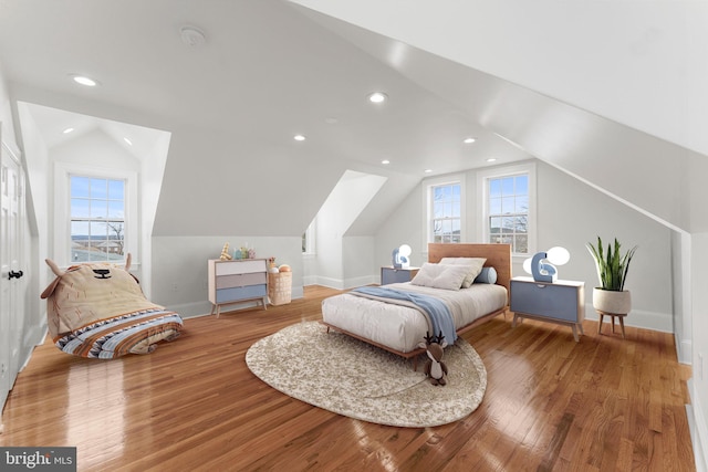 bedroom featuring lofted ceiling, wood-type flooring, and multiple windows