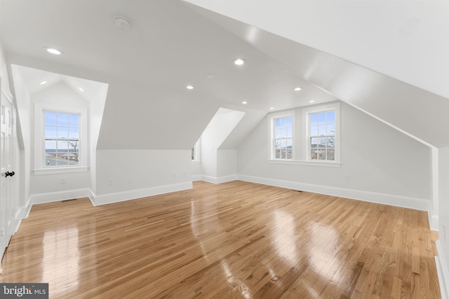 additional living space featuring lofted ceiling, a wealth of natural light, and light wood-type flooring