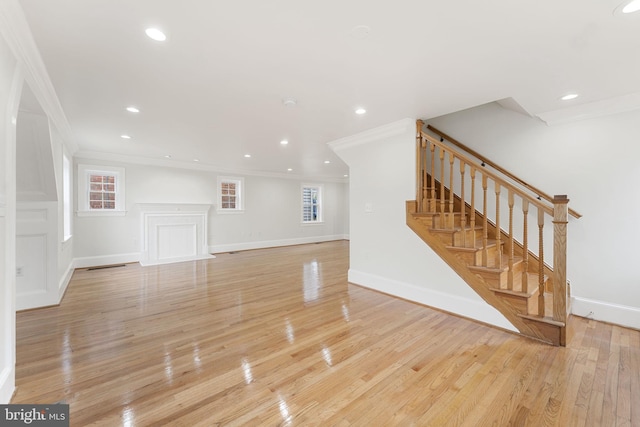 unfurnished living room with ornamental molding and light hardwood / wood-style floors