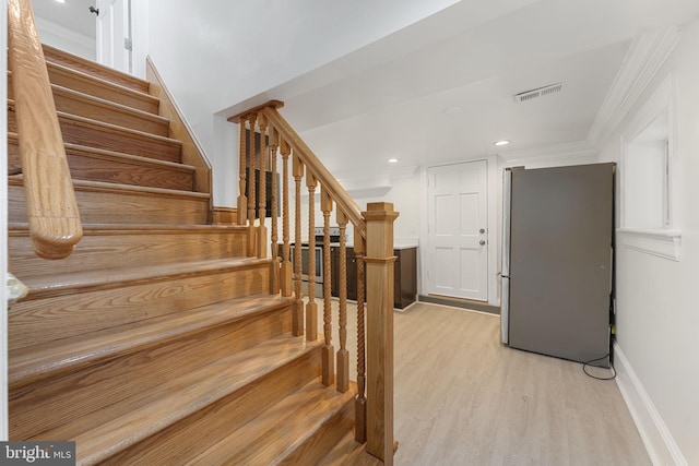 stairs featuring crown molding and hardwood / wood-style flooring