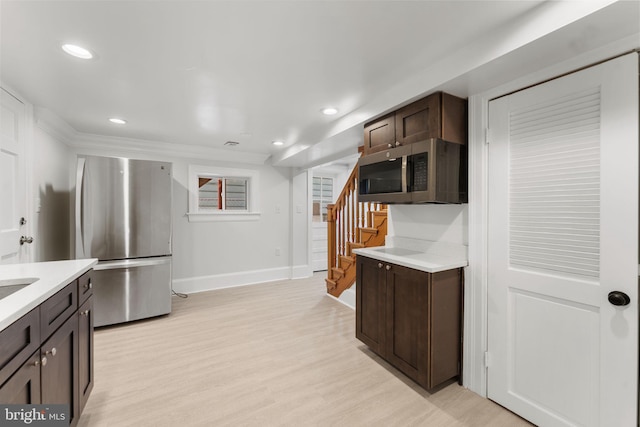 kitchen with stainless steel appliances, dark brown cabinets, and light wood-type flooring