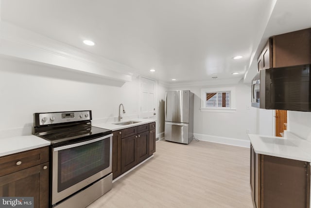 kitchen with appliances with stainless steel finishes, sink, dark brown cabinetry, crown molding, and light wood-type flooring