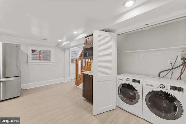 laundry area featuring independent washer and dryer and light hardwood / wood-style flooring