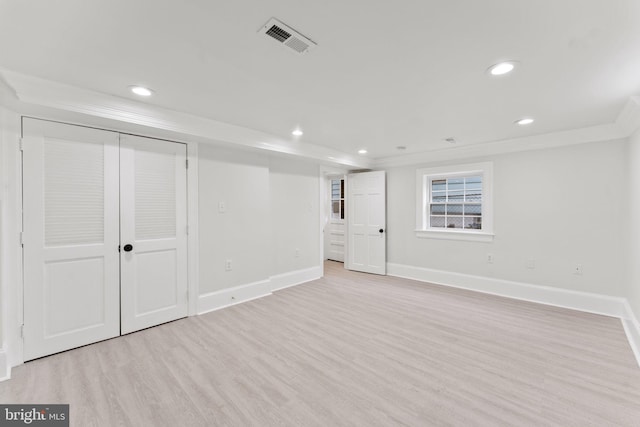 basement with light hardwood / wood-style flooring and ornamental molding