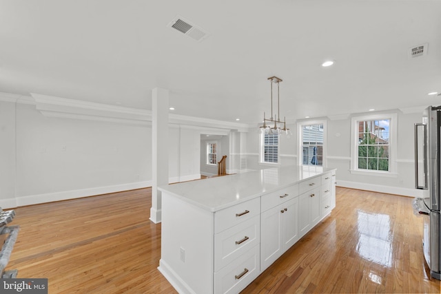 kitchen with white cabinetry, a center island, light hardwood / wood-style floors, and hanging light fixtures