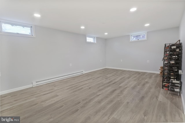 basement with light wood-type flooring and baseboard heating