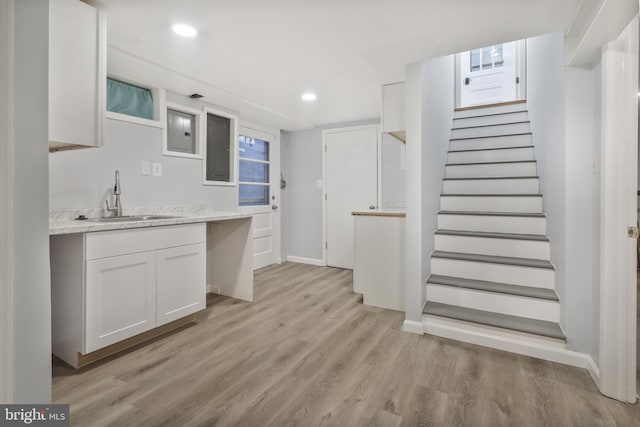 kitchen featuring light wood-type flooring, white cabinetry, and sink