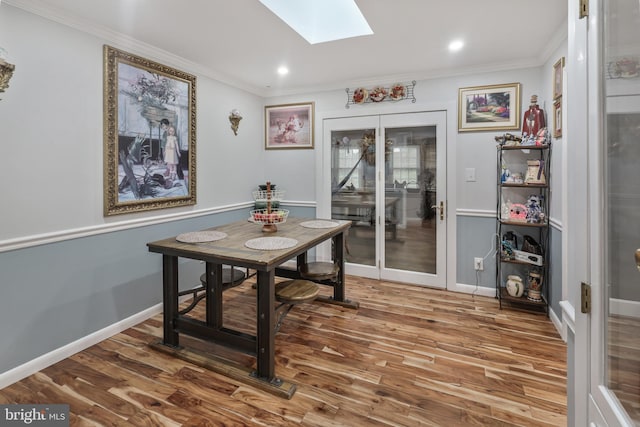 dining space featuring hardwood / wood-style floors, crown molding, and a skylight