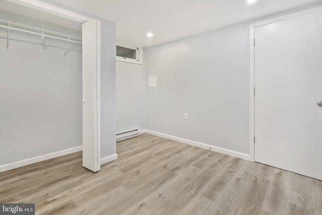 unfurnished bedroom featuring a closet, light hardwood / wood-style flooring, and a baseboard radiator