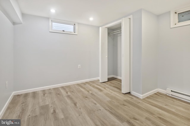 basement with light hardwood / wood-style floors and a baseboard heating unit