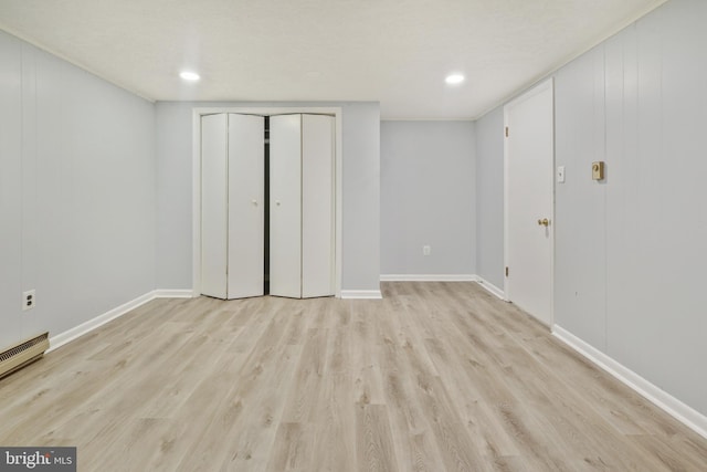 unfurnished bedroom featuring light hardwood / wood-style floors, a textured ceiling, and a baseboard heating unit