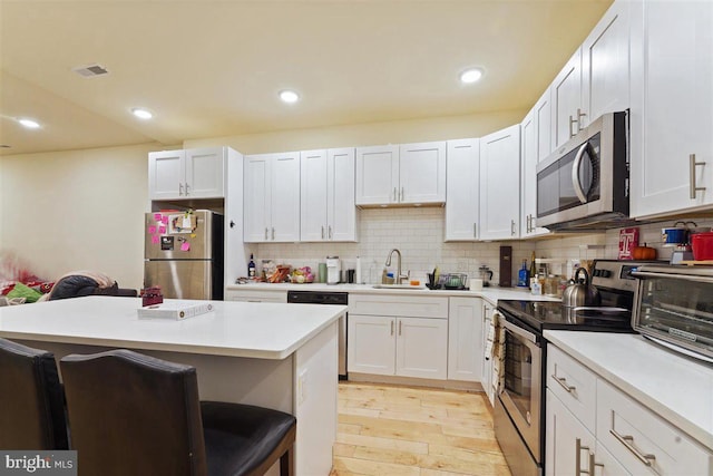 kitchen featuring appliances with stainless steel finishes, white cabinets, sink, and a breakfast bar area