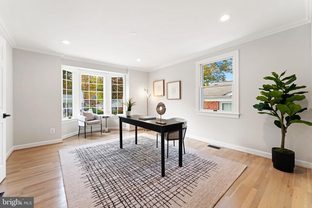 office space with ornamental molding, a healthy amount of sunlight, and light wood-type flooring