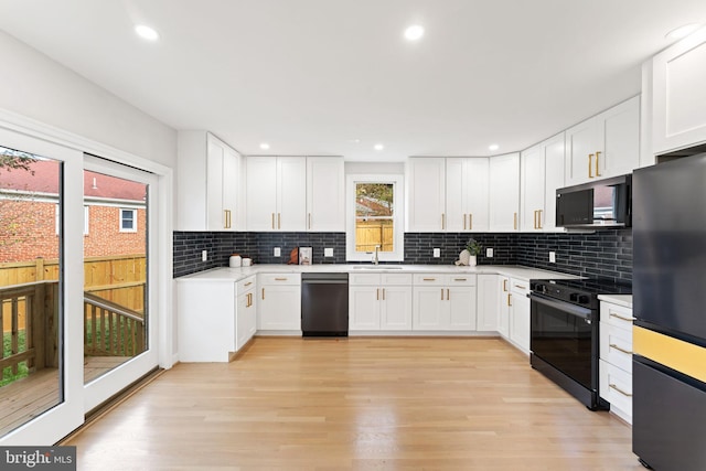 kitchen featuring backsplash, white cabinetry, light wood-type flooring, black appliances, and sink