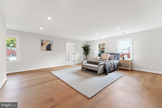 bedroom with ensuite bath and light hardwood / wood-style flooring