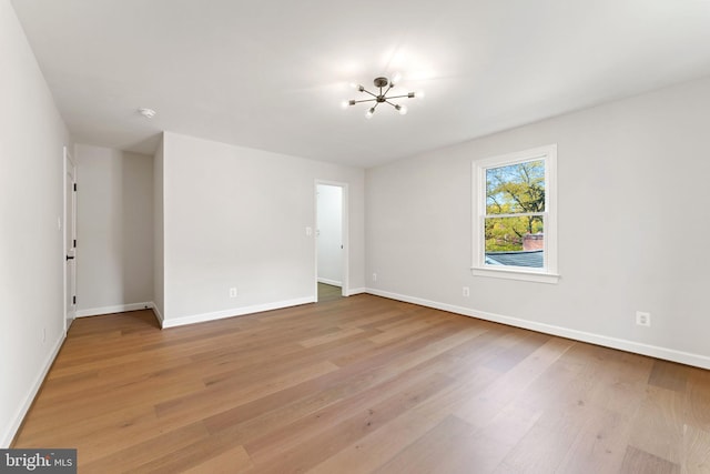 spare room featuring an inviting chandelier and light hardwood / wood-style floors