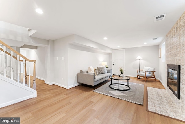 living room with a tiled fireplace and light hardwood / wood-style floors