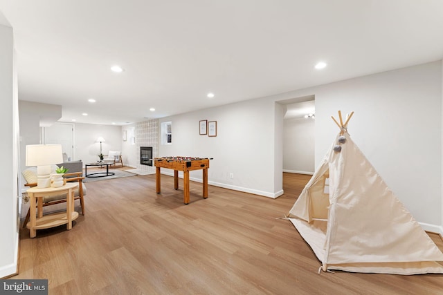 game room with a fireplace and light hardwood / wood-style floors