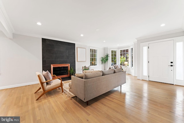 living room with crown molding, a tile fireplace, and light wood-type flooring