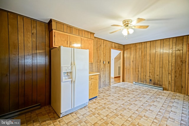 kitchen featuring wooden walls, white refrigerator with ice dispenser, a baseboard radiator, and ceiling fan