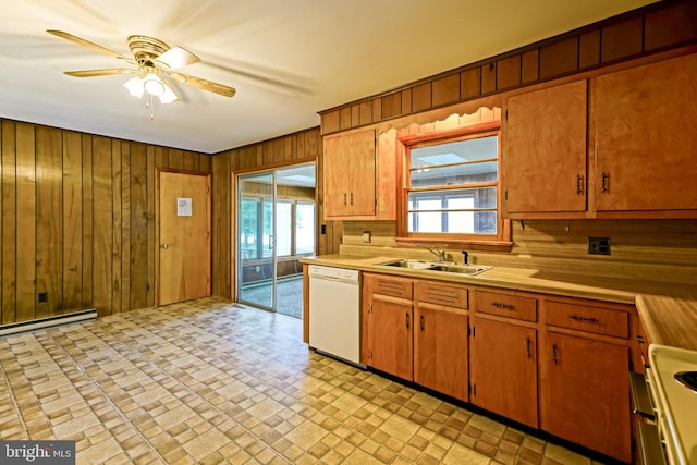 kitchen with sink, dishwasher, a healthy amount of sunlight, and wooden walls