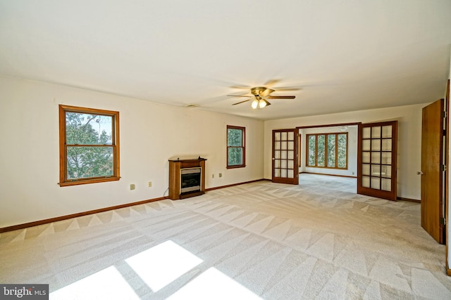 unfurnished living room with french doors, light colored carpet, and ceiling fan