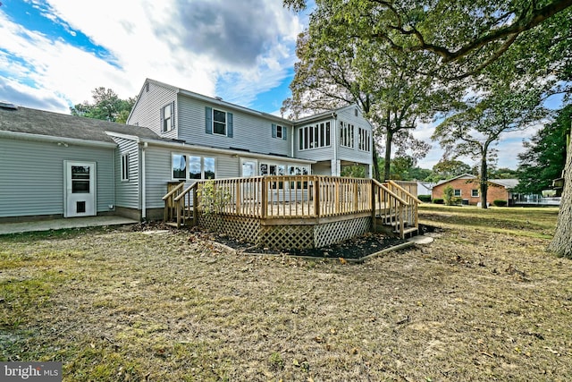 rear view of property featuring a wooden deck and a lawn