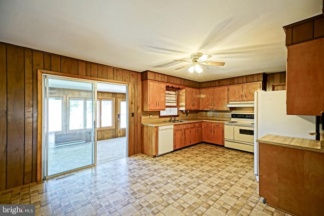 kitchen featuring sink, wooden walls, white appliances, and ceiling fan