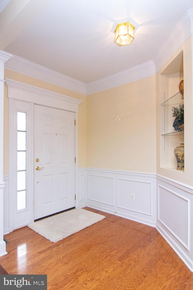 entryway with ornamental molding and wood-type flooring