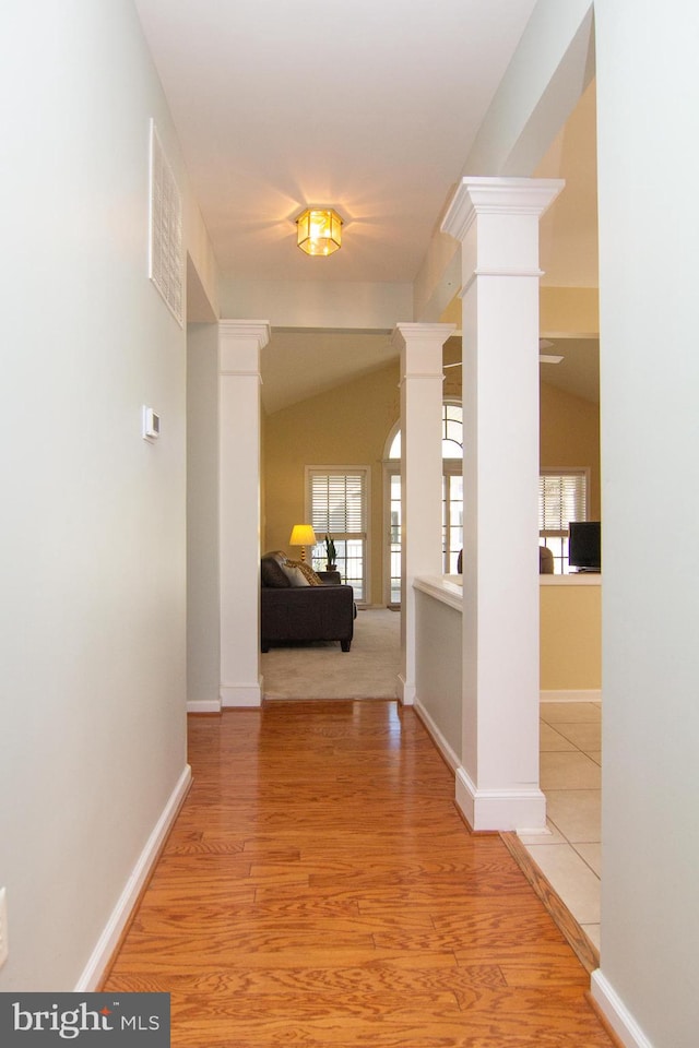 corridor with vaulted ceiling, hardwood / wood-style flooring, and a wealth of natural light