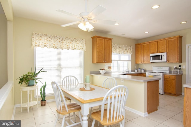 kitchen featuring kitchen peninsula, ceiling fan, light tile patterned floors, and white appliances