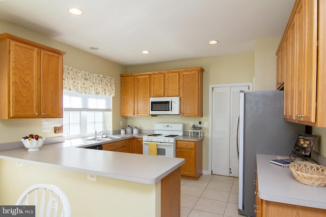 kitchen featuring kitchen peninsula, sink, light tile patterned floors, and white appliances