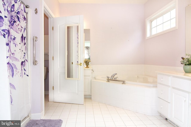 bathroom featuring vanity, a relaxing tiled tub, and tile patterned flooring