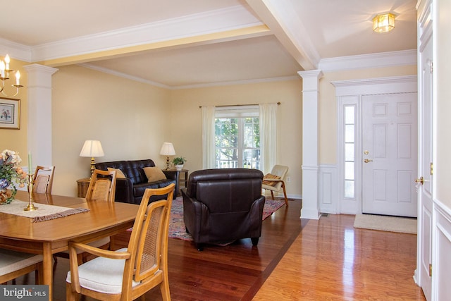 dining area with a notable chandelier, crown molding, ornate columns, and hardwood / wood-style flooring