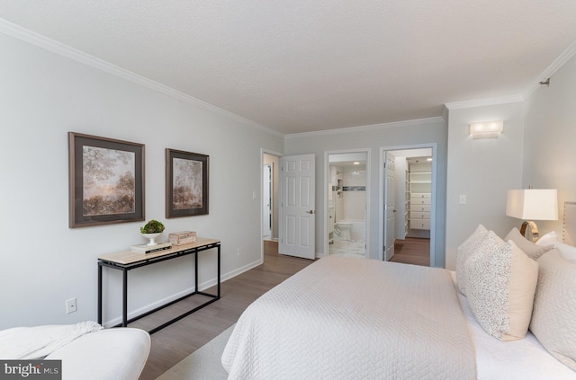 bedroom featuring connected bathroom, crown molding, a spacious closet, and hardwood / wood-style flooring