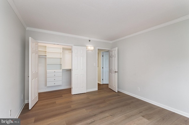 unfurnished bedroom featuring crown molding, a closet, and wood-type flooring