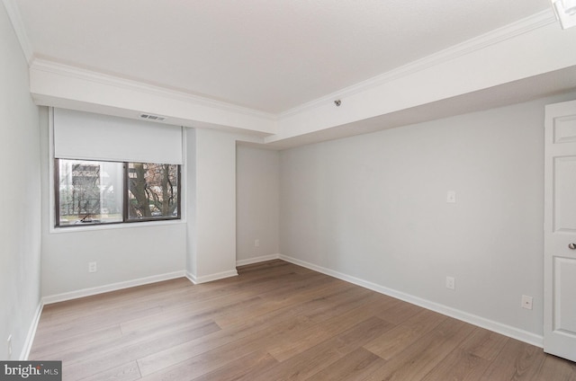 empty room featuring light wood-type flooring and ornamental molding