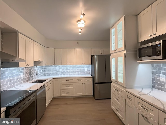 kitchen featuring white cabinets, sink, light stone countertops, tasteful backsplash, and stainless steel appliances