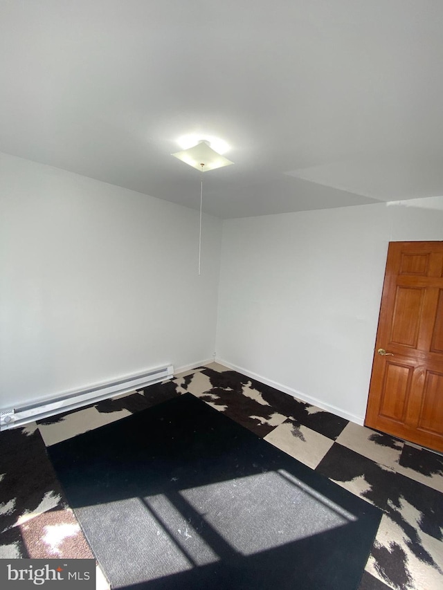 unfurnished room with baseboard heating and dark colored carpet