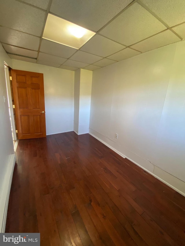 empty room with a paneled ceiling and dark wood-type flooring