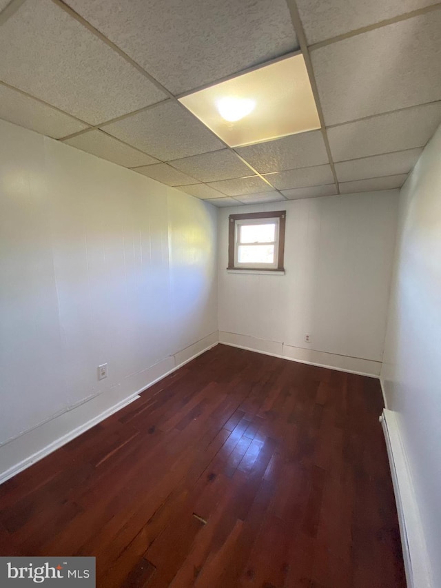 spare room with a drop ceiling, dark hardwood / wood-style floors, and baseboard heating