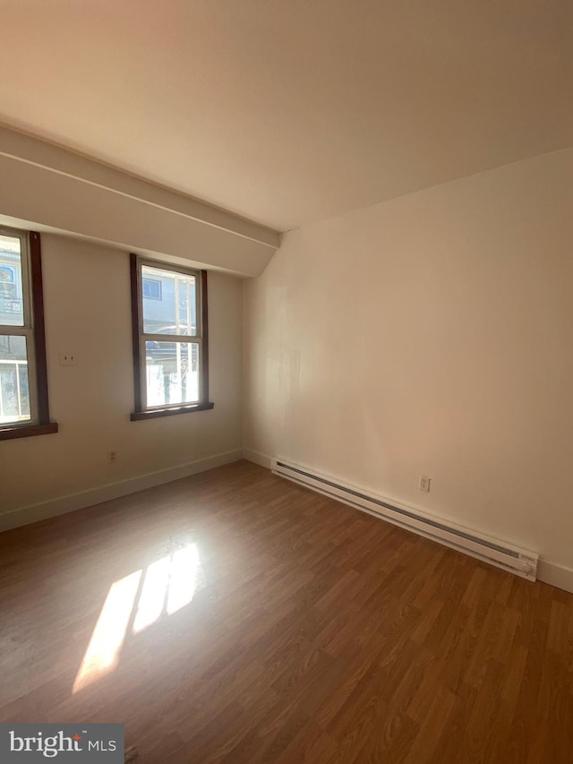 empty room with baseboard heating and hardwood / wood-style flooring