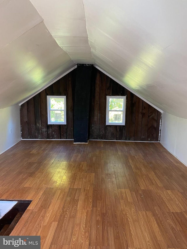 additional living space featuring a wealth of natural light, hardwood / wood-style floors, and wood walls