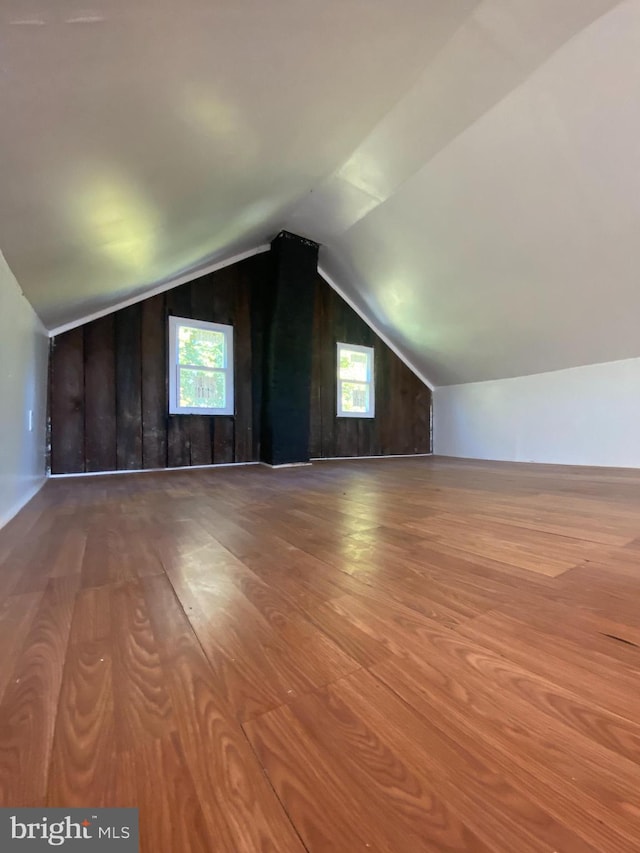 bonus room featuring wood walls, wood-type flooring, and vaulted ceiling