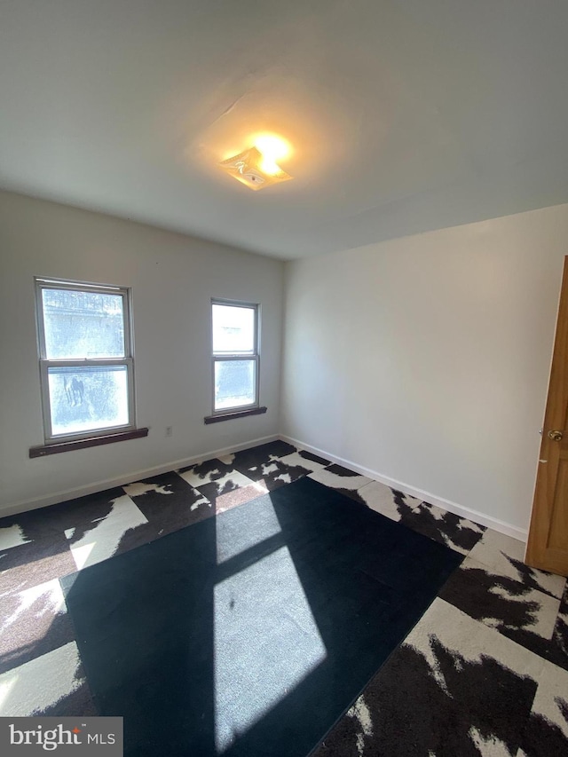 empty room with baseboards and carpet