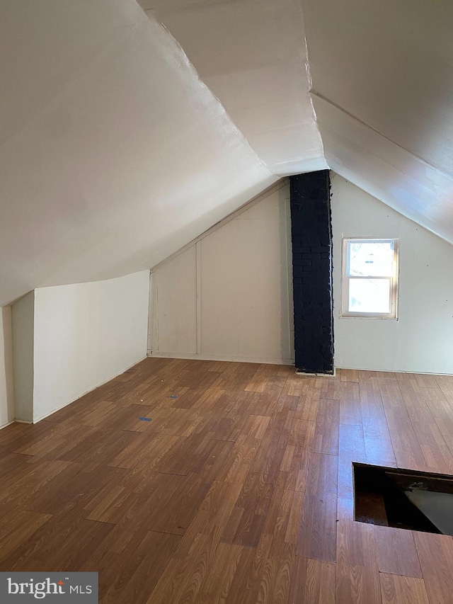 additional living space with hardwood / wood-style floors and vaulted ceiling