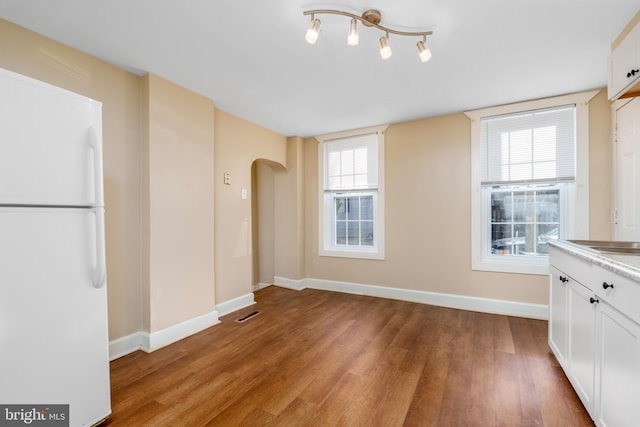 interior space with white fridge, light hardwood / wood-style floors, plenty of natural light, and white cabinets